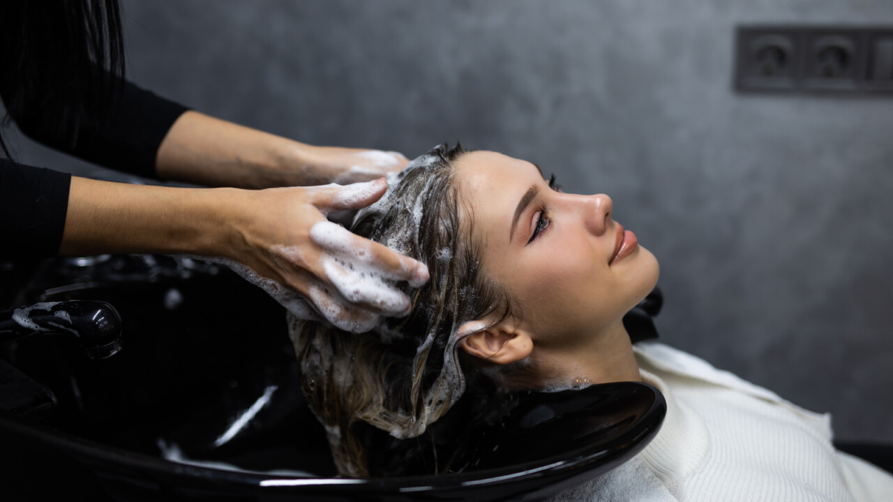 beauty and people Happy young woman with hairdresser washing head at hair salon